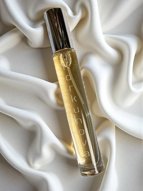 A bottle of Korkunova Vanilla Dream pheromone perfume laying on a plush white fabric with gold snowflakes